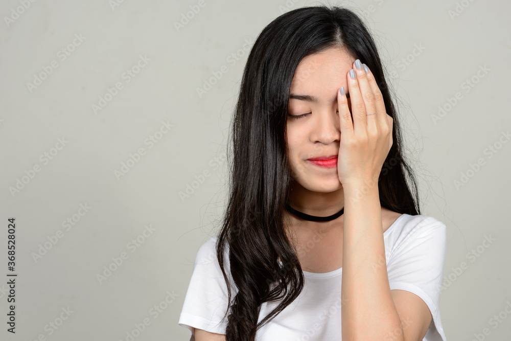 Portrait of young beautiful Asian woman against white background