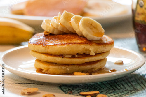 delicious banana pancake breakfast topped with almonds, syrup, and bananas