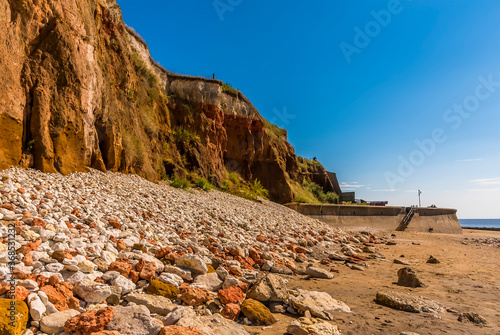 A view across major rockfalls from the white, red and orange stratified cliffs towards the sea wall at Old Hunstanton, Norfolk, UK photo