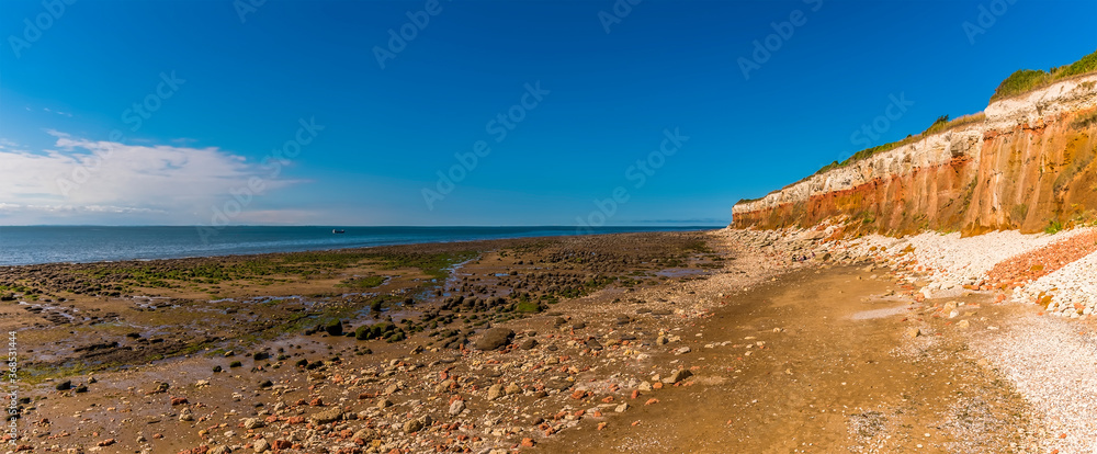 A view across the beach and along the white, red and orange stratified cliffs at Old Hunstanton, Norfolk, UK