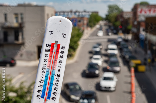 Thermometer in front of cars and traffic during heatwave in Montreal.