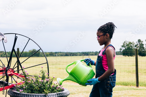 Young girl watering plants on farm