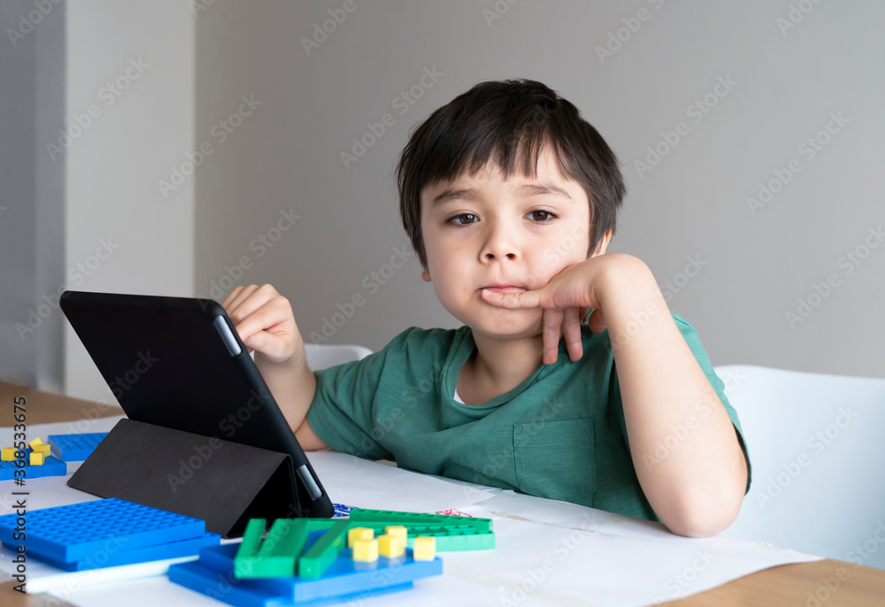 Kid learning math online on tablet and using plastic block counting number, Child boy studying math by colour stack box, Home schooling, Distance learning or online education concept Kid learning math online on tablet and using plastic block counting number, Child boy studying math by colour stack box, Home schooling, Distance learning or online education concept