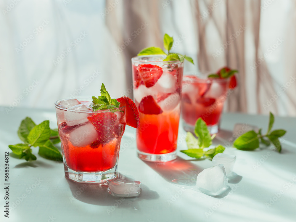Glasses of strawberry cocktail or mocktail, refreshing summer drink with crushed ice and sparkling water on a light background. Beverage photography. Glasses of strawberry cocktail or mocktail, refreshing summer drink with crushed ice and sparkling water on a light background. Beverage photography.