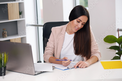 lovely young businesswoman sitting in modern office, brunette