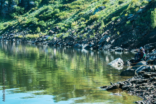 fishermen fishing on the shore of a blue lake