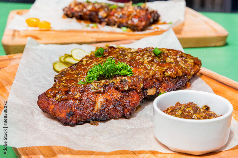 Close up board with pork ribs grilled with BBQ sauce, peanuts and jalapeno Close up board with pork ribs grilled with BBQ sauce, peanuts and jalapeno