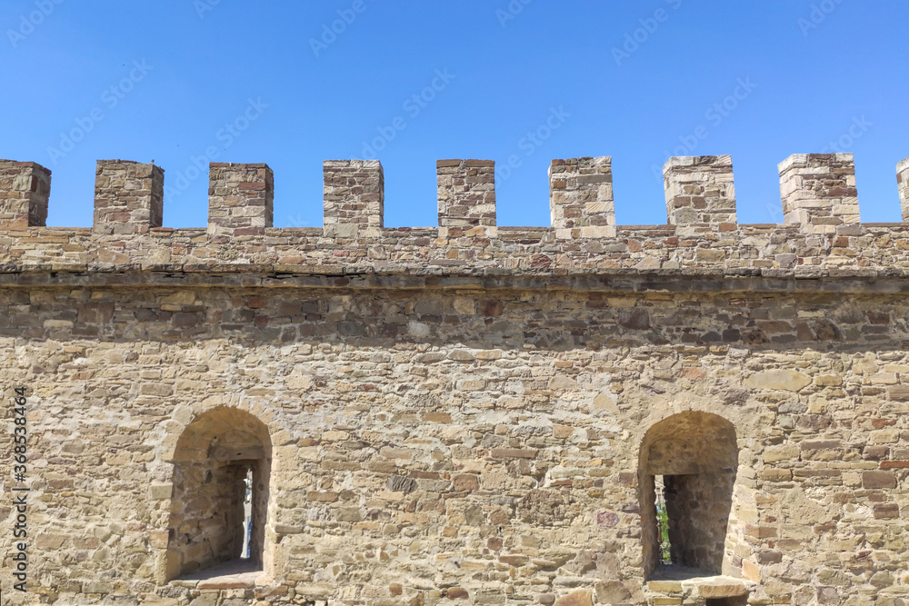 Fragment of a castle wall of a fortress fortification made of natural stone. Middle Ages