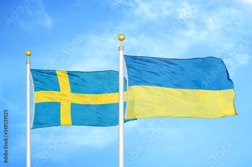 Sweden and Ukraine two flags on flagpoles and blue sky