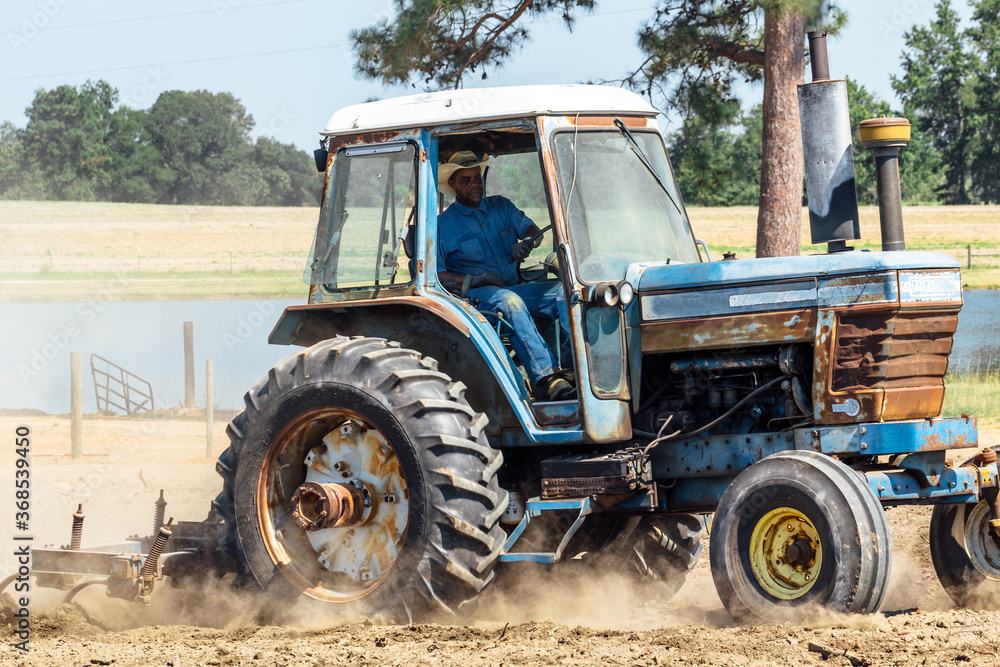 Man driving tractor through field clearing for new crop planting Man driving tractor through field clearing for new crop planting