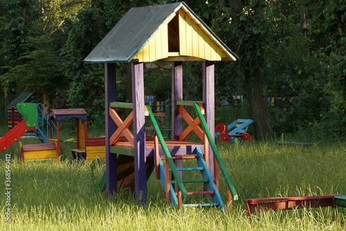 colored wooden house with a ladder on the playground in the green grass