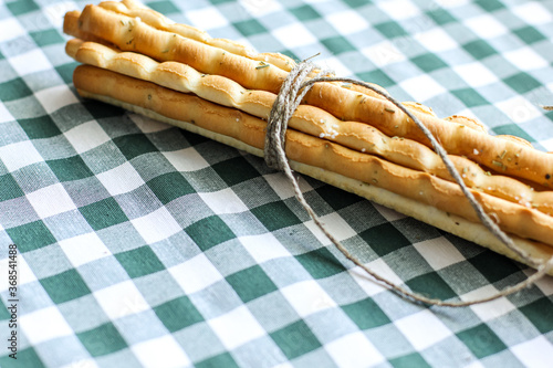 Breadsticks or Italian grissini snack on green gingham tablecloth. Food, gastronomy, cuisine, culture concept. Copy space. 