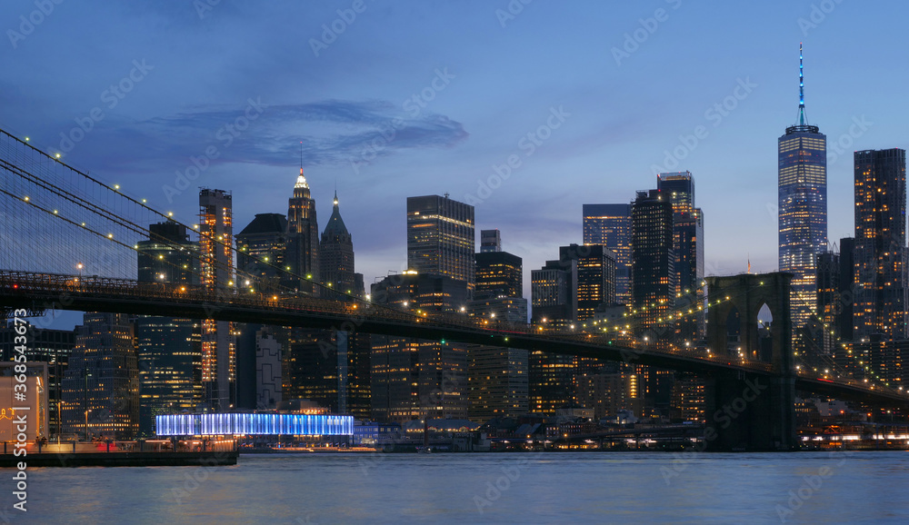 Naklejka premium landscape of lower manhattan with Brooklyn bridge east river at night time