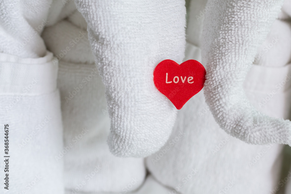 a wooden red heart holding an elephant figurine of a white towel symbol of love composition greeting the newlyweds in a hotel
