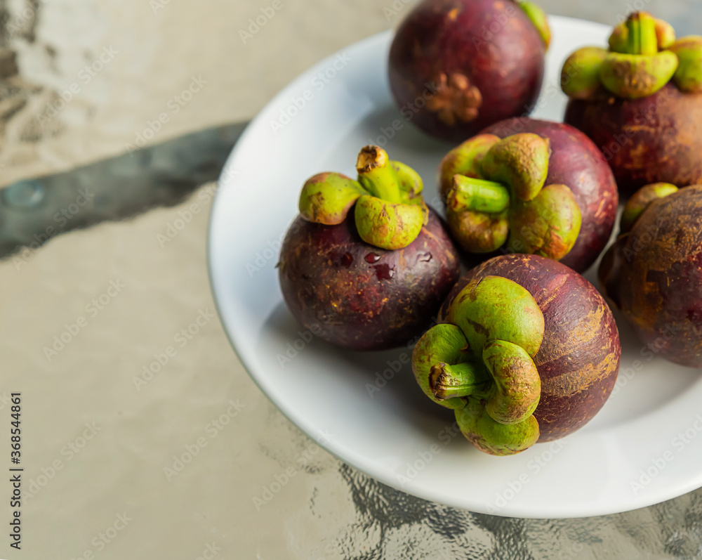 fresh round fruit mangosteen delicious lies on a plate standing on a transparent table fresh round fruit mangosteen delicious lies on a plate standing on a transparent table