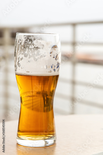 glass of cold lager beer vertical photo on the blurred background of the summer cafe
