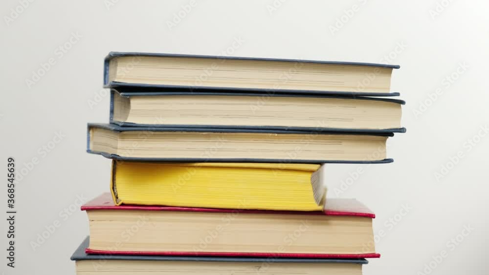 stack of various hardback books, hand stacks books on top of each other on white background, reading concept stack of various hardback books, hand stacks books on top of each other on white background, reading concept