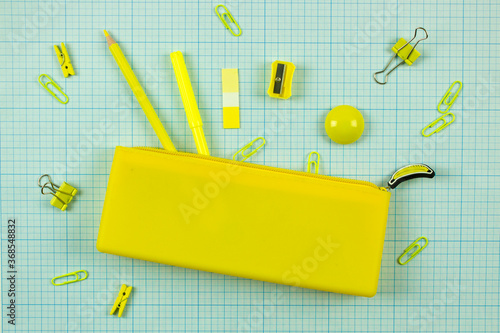 bright yellow school pencil case and stationery on scaled coordinate paper. school educational concept