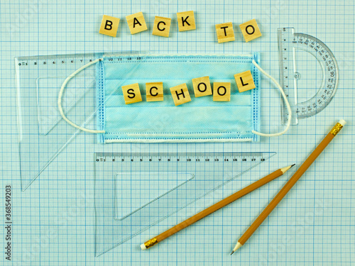 Back to school and a medical mask. social distance and education. scaled coordinate paper, ruler, protractor and pencil