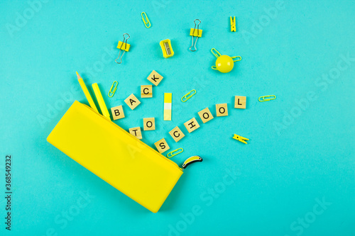 bright yellow stationery and a back to school sign tumbled out of the pencil case. blue background.school theme.new school year and knowledge day