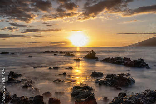 Low angle Sunset on beach in Hawaii Maui Long exposure of waves coming in.