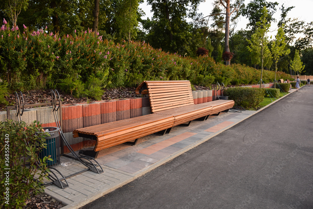 Large empty wooden brown bench in summer park Large empty wooden brown bench in summer park