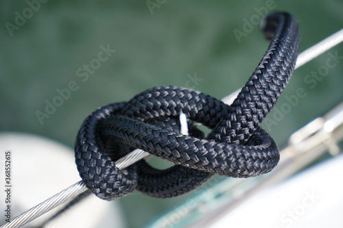 Mast throw in a blue nautical line. Button fastening for fender from sailyacht. Blue rope in strong knot.