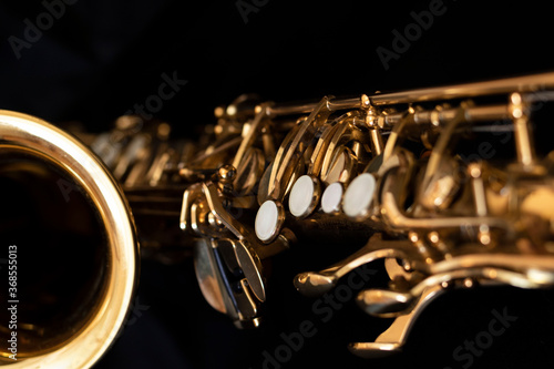 A close up of a saxophone with a black background.