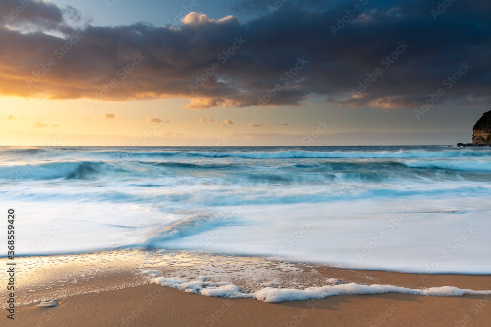 Sunrise at the beach with waves and clouds