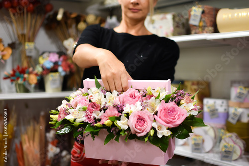 woman florist with flower arrangement in wooden decorative box