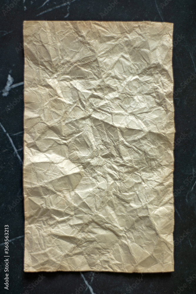 rumpled sheet of old paper on a black background rumpled sheet of old paper on a black background