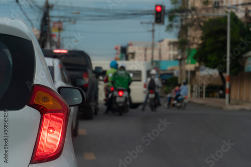Close up of car rear light stop and wait for the traffic lights at the intersection. With blurry images of cars and motorcycles waiting in the queue in front.