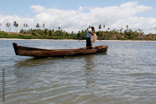 conde, bahia / brazil - march 28, 2013: fishermen are seen in a small boat near the mouth of the Itapicuru river in the district of Siribinha in the city of Conde, north coast of Bahia. photo