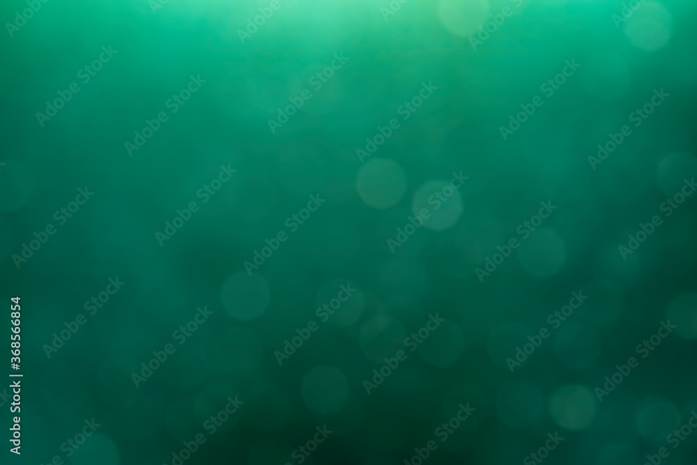 Defocused abstract Green bokeh on a dark background. Blurred holiday bokeh.