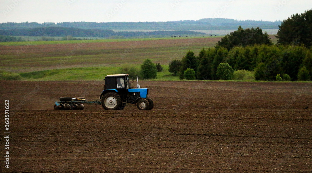 large tractor with plow plows field before spring sowing of crops. tractor with harrow drives across plowed field and levels arable land. large tractor with plow plows field before spring sowing of crops. tractor with harrow drives across plowed field and levels arable land.