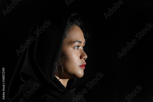 Young beautiful modern Malay woman head scarf on black background look forward side face