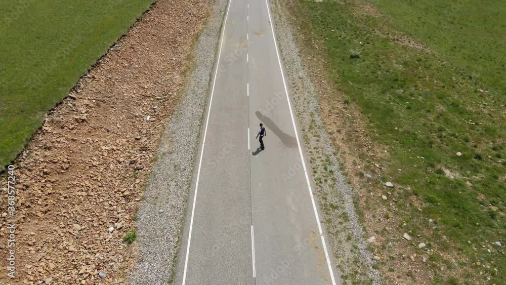 guy in summer in black clothes descends from the mountain on a skateboard against the background of the snow-covered mountain elbrus guy in summer in black clothes descends from the mountain on a skateboard against the background of the snow-covered mountain elbrus