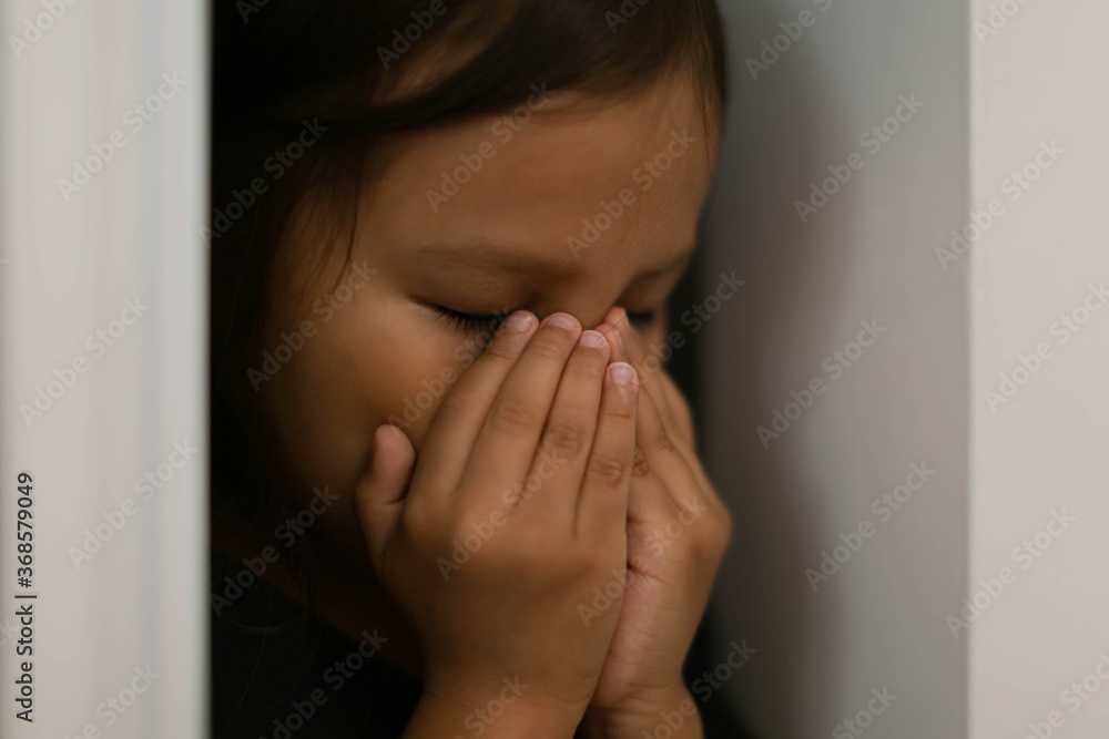 Depressed little girl crying a lone at home. Domestic abuse.