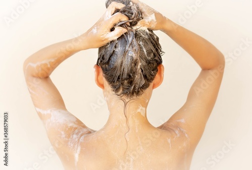 A pretty woman washing her hair with shampoo.