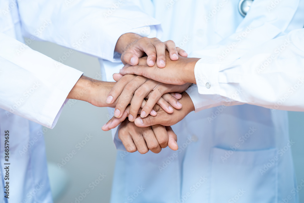 Portrait of medical team piling hands together in a symbol of unity. Portrait of medical team piling hands together in a symbol of unity.