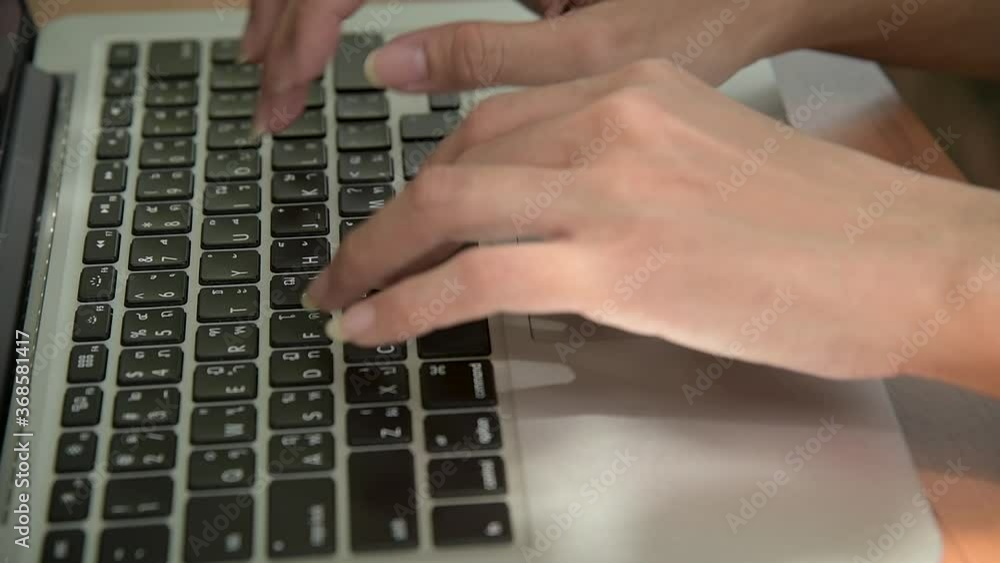 The close-up of a woman's hand is using a laptop keyboard while working. The close-up of a woman's hand is using a laptop keyboard while working.