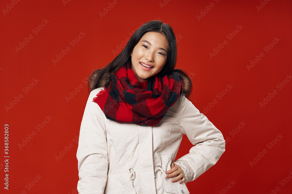 Woman in winter clothes checkered scarf smile asian appearance red isolated background Woman in winter clothes checkered scarf smile asian appearance red isolated background