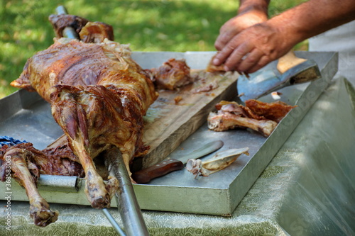 Canvastavla Man's hands cutting whole lamb baked on a spit