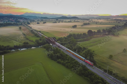 Express passenger train from Prague to Rijeka on its way over the Ljubljana marshes in early romantic morning with sunrise.