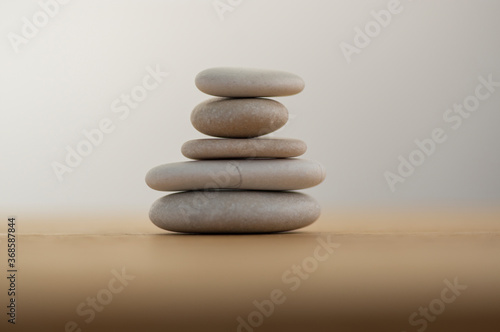 Stone cairn on striped grey white background  five stones tower  simple poise stones  simplicity harmony and balance 