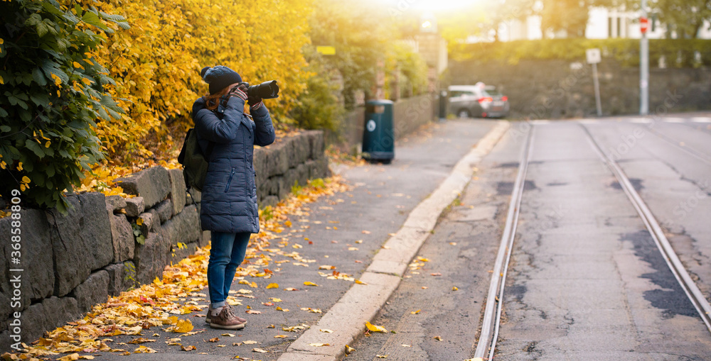 Woman tourist photographing autumn city street
