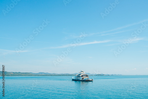 A white ferry carrying a crew and many cars sailing in the ocean on sunny day with clear skies. Indigo seawater with soft tone. Feeling fresh and relaxing. Ideas for holiday travel. Copy space on top. © Pang wrp