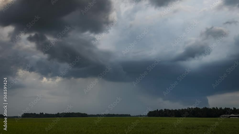 Time lapse of storm clouds moving over farmland grassland farming meadow field. Summer storm forming. Rain rainfall cloud motion day thunderstorm. Wide, static, low angle Time lapse of storm clouds moving over farmland grassland farming meadow field. Summer storm forming. Rain rainfall cloud motion day thunderstorm. Wide, static, low angle