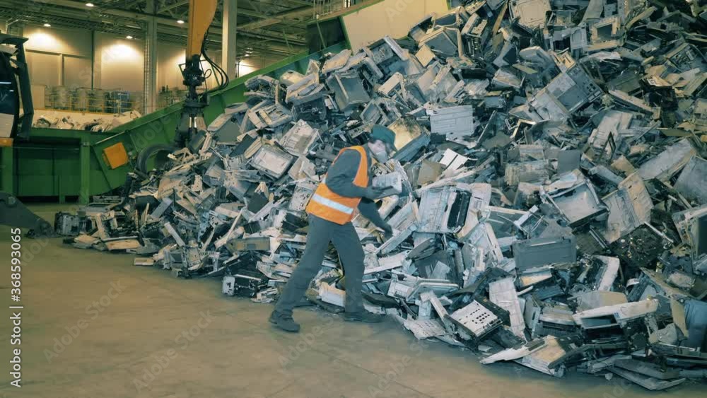 Male worker checks garbage at recycling factory. Male worker checks garbage at recycling factory.