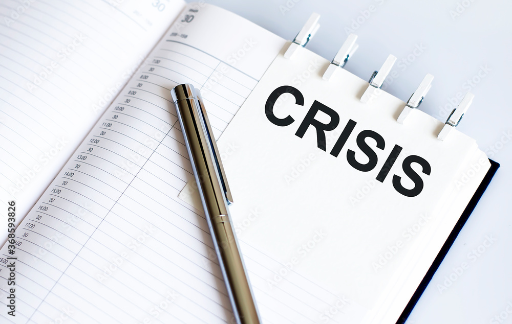 text CRISIS on the short note texture background with pen text CRISIS on the short note texture background with pen